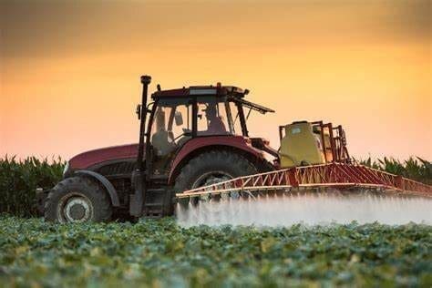Trator agrícola pulveriza alguma substância em plantação.