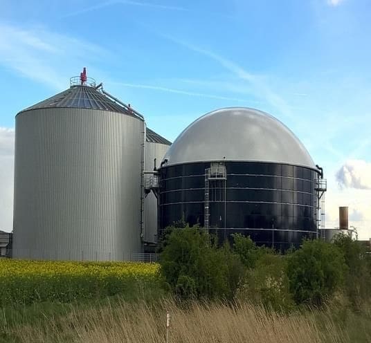 Instalação industrial para conversão de lixo em combustível, com tanques metálicos e unidade de processamento térmico, representando a Biodigestão Anaeróbica.
