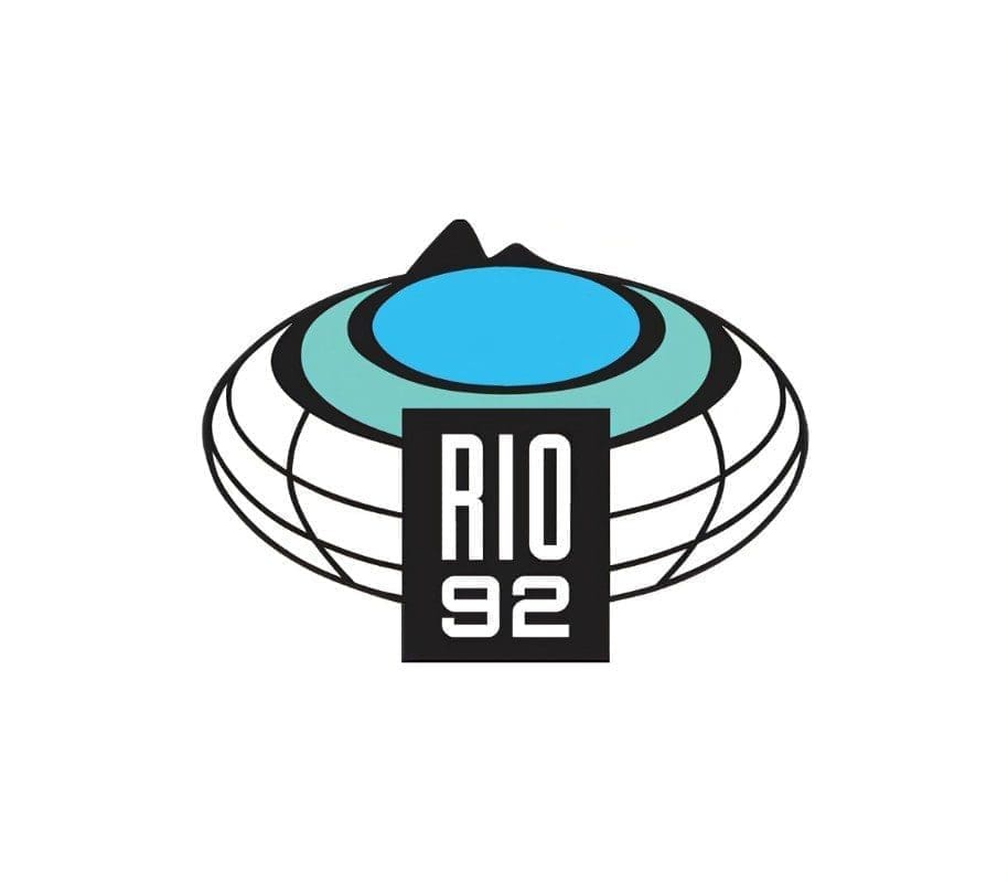 logomarca da Agenda - Eco 92 - Rio, apresenta um globo terrestre achatado, em tons de branco, verde e azul; e a inscrição "Rio 92" a frente.