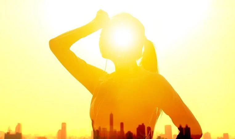 A sombra de uma mulher envolta por fortes raios solares representa bem os eventos cliáticos extremos que acontecem cada vez mais