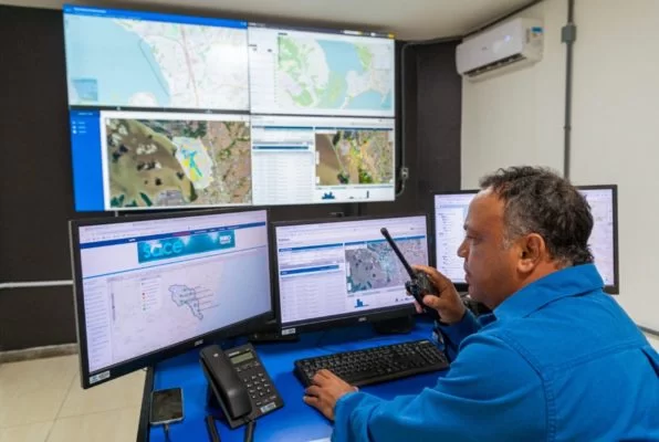 Um homem sentado em frente a várias telas computacionais, representando o Sistema de alerta de desastres no Brasil