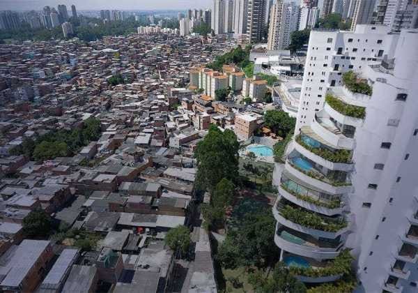 Cidade vista de cima explicitando a segregação socioambiental, de um lado prédios luxuosos e de outro, casas pobres.