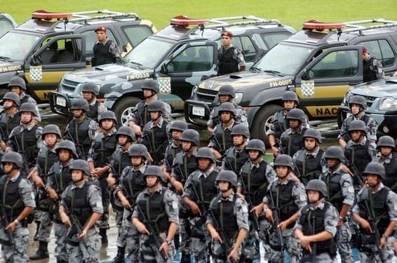 Foto representativa da Violência e segurança pública no Brasil, viaturas da polícia lado a lado e à frente vários soldados da polícia militar.