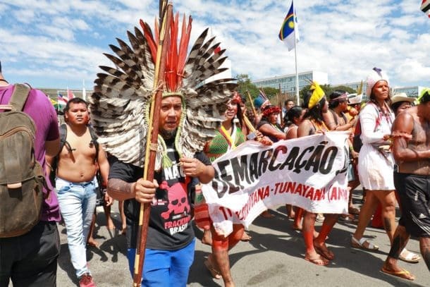 Povos originários protestando em via pública pelos direitos indígenas.