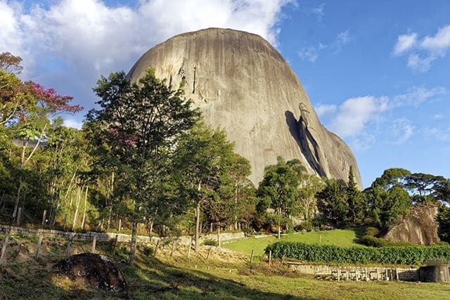 mostra uma grande pedra em um campo representando o Parque Estadual da Pedra Azul