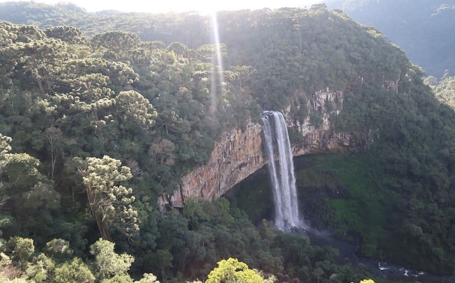 No Parque Estadual do Caracol cachoeira desce de serra com densa vegetação