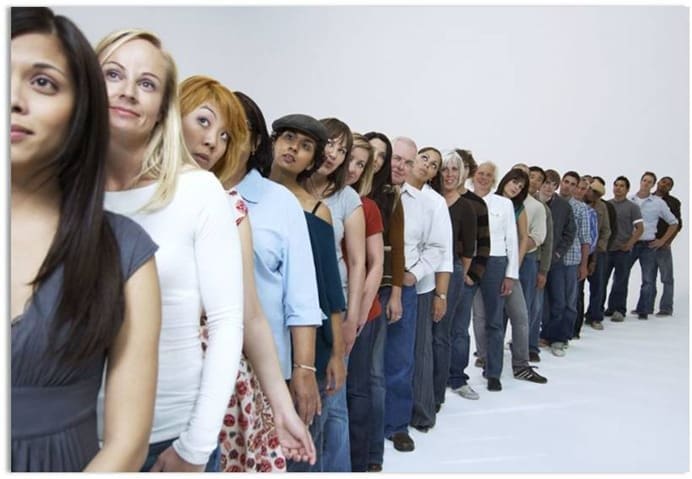 Segregação cultural: uma fila com várias pessoas, dentre elas, pessoas brancas, negras, pardas. A primeira pessoa da fila é uma mulher branca e a última, um homem negro.