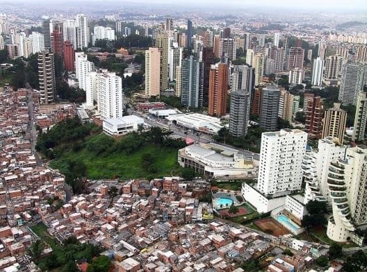 Cidade vista de cima evidenciando a segregação espacial, casas pobres de um lado e do outro, prédios de luxo.