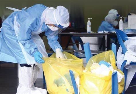 Pessoas paramentadas com roupas de segurança biológica recolhem resíduos urbanos contaminados. O que é importante para a saúde pública.