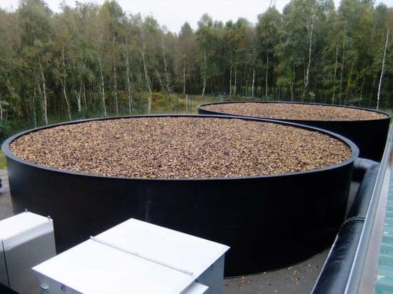 Em um ambiente rural vê-se dois tanques que formam um sistema de biofiltro